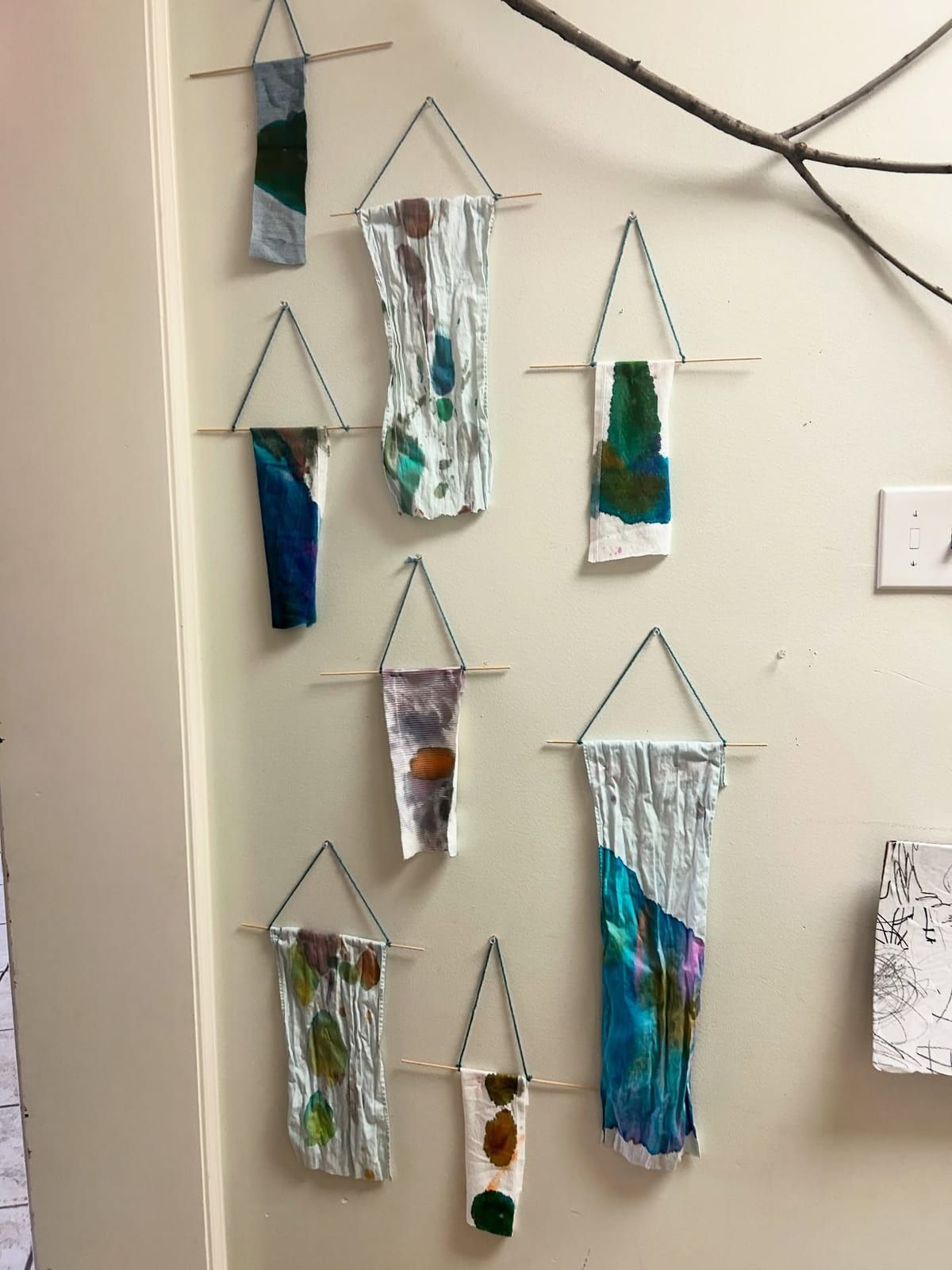 Small painted fabric banners hung from sticks on a classroom wall.